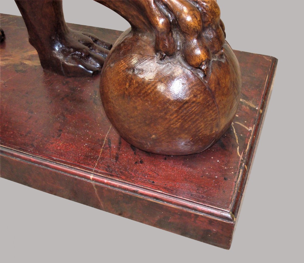 A pair of nineteenth-century carved wooden Medici lions depicted standing with one paw resting on a sphere, mounted on reddish marbled rectangular bases. View XVII