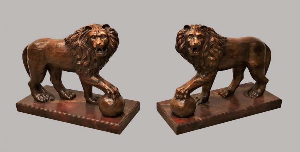 A pair of nineteenth-century carved wooden Medici lions depicted standing with one paw resting on a sphere, mounted on reddish marbled rectangular bases. View XIX