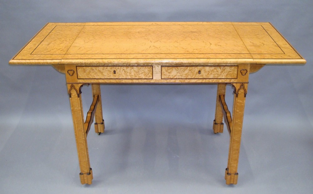 A nineteenth-century French birds eye maple sofa table featuring drop-leaf ends, twin drawers, Gothic Revival spandrels, and a low stretcher with trefoil inlay. View II