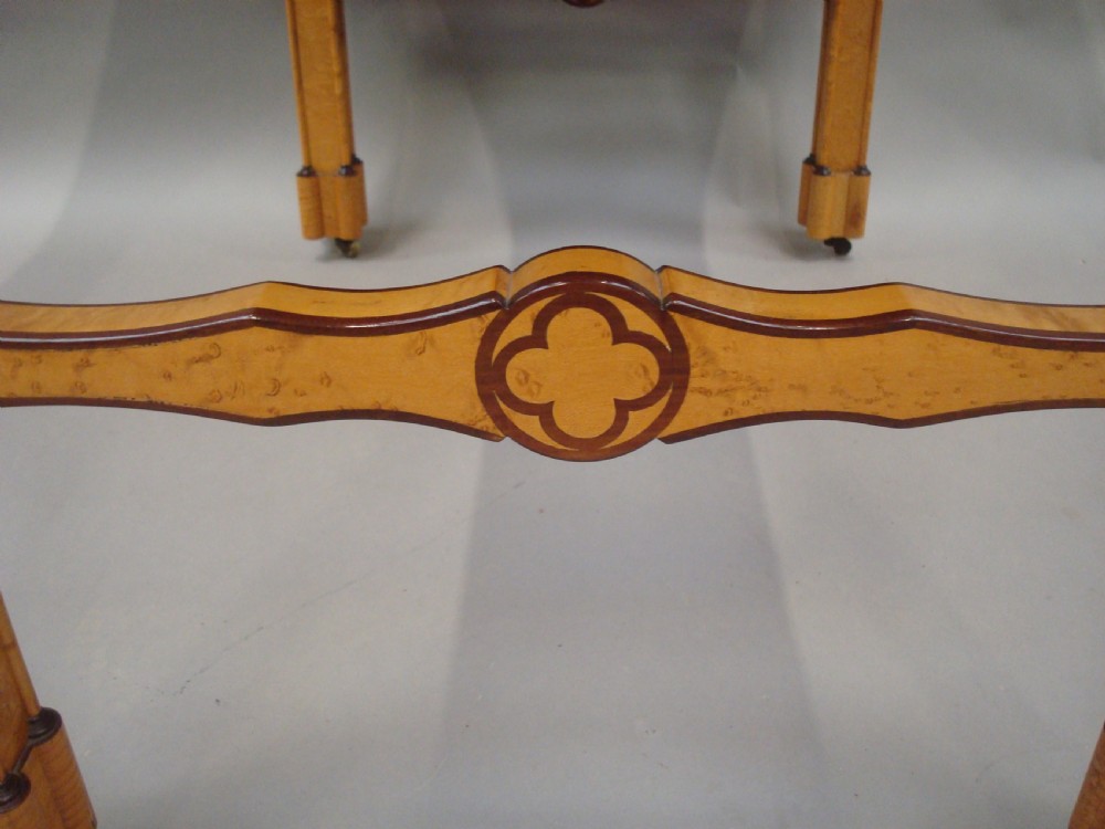 A nineteenth-century French birds eye maple sofa table featuring drop-leaf ends, twin drawers, Gothic Revival spandrels, and a low stretcher with trefoil inlay. View IX