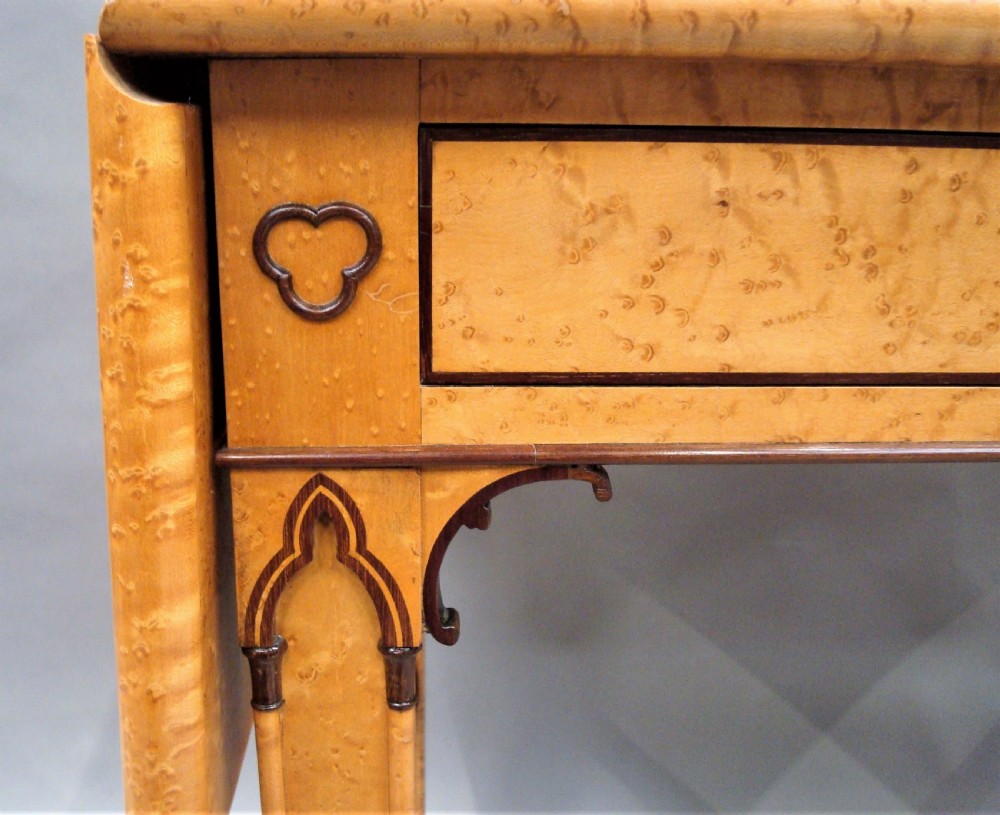 A nineteenth-century French birds eye maple sofa table featuring drop-leaf ends, twin drawers, Gothic Revival spandrels, and a low stretcher with trefoil inlay. View X