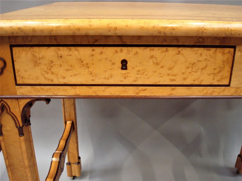 A nineteenth-century French birds eye maple sofa table featuring drop-leaf ends, twin drawers, Gothic Revival spandrels, and a low stretcher with trefoil inlay. View XII