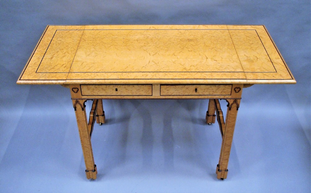 A nineteenth-century French birds eye maple sofa table featuring drop-leaf ends, twin drawers, Gothic Revival spandrels, and a low stretcher with trefoil inlay. View XVIII