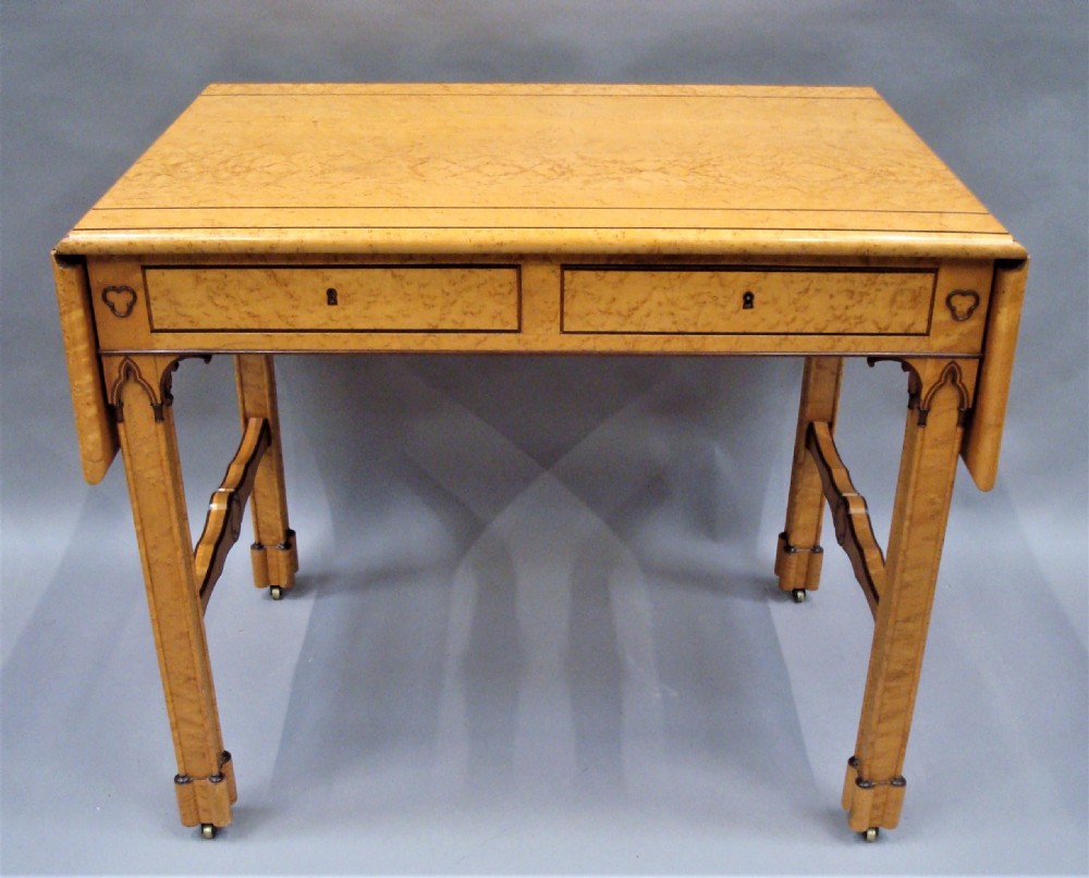 A nineteenth-century French birds eye maple sofa table featuring drop-leaf ends, twin drawers, Gothic Revival spandrels, and a low stretcher with trefoil inlay. View XIX