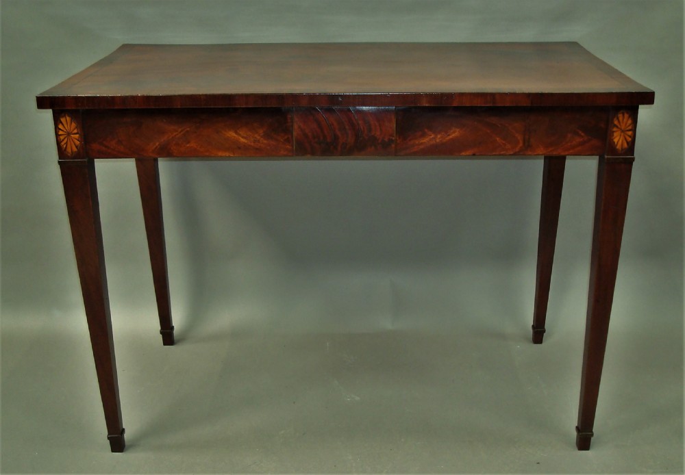 A George III mahogany side table featuring a rectangular top, flame mahogany frieze, patera marquetry corner inlays, and square tapered legs.