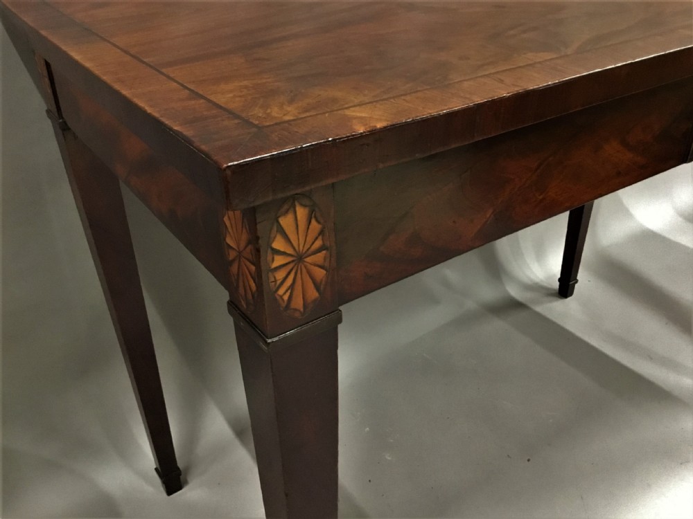 A George III mahogany side table featuring a rectangular top, flame mahogany frieze, patera marquetry corner inlays, and square tapered legs. View XIII