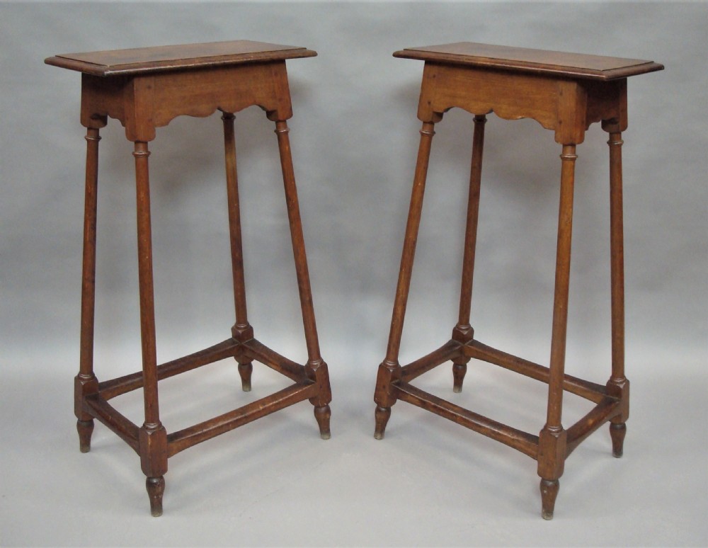 A pair of tall 19th-century oak stands featuring rectangular tops, scalloped aprons, slender turned legs, and low box stretchers.
