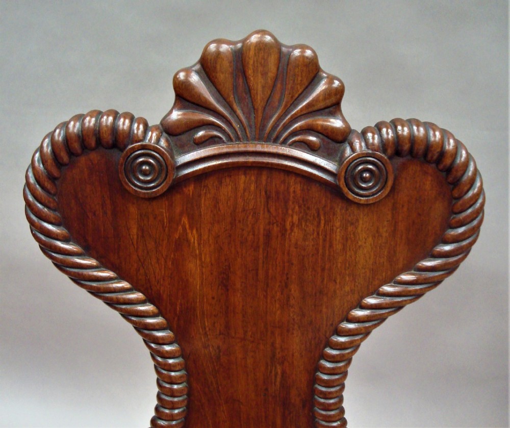 A pair of Regency mahogany hall chairs featuring carved shell cresting, rope-twist backrest borders, solid seats, and spiral-turned front legs. View VIII