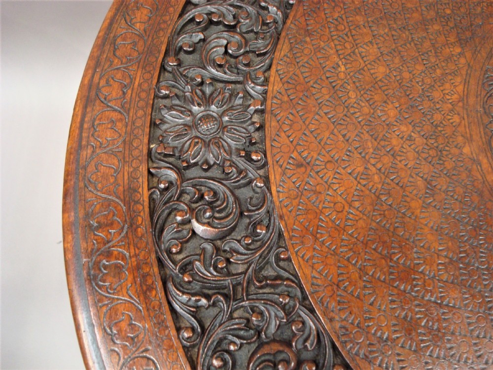 A 19th-century carved teak round table supported by a tripod base shaped like three elephant heads with curving trunks. View XII