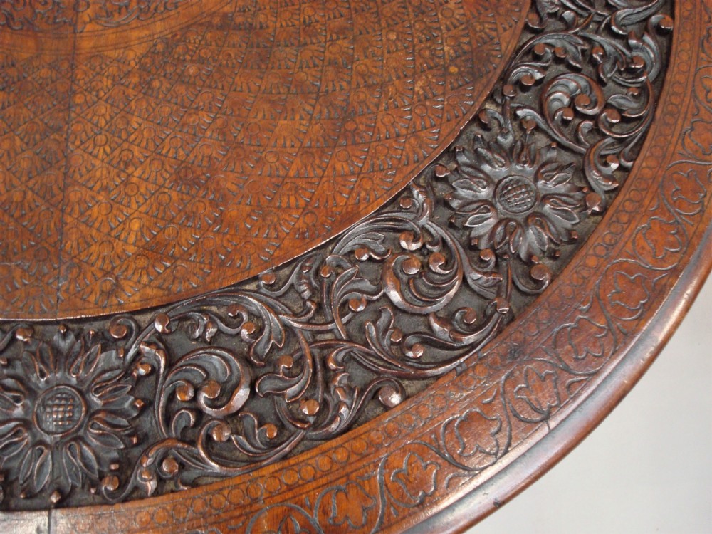 A 19th-century carved teak round table supported by a tripod base shaped like three elephant heads with curving trunks. View XIII