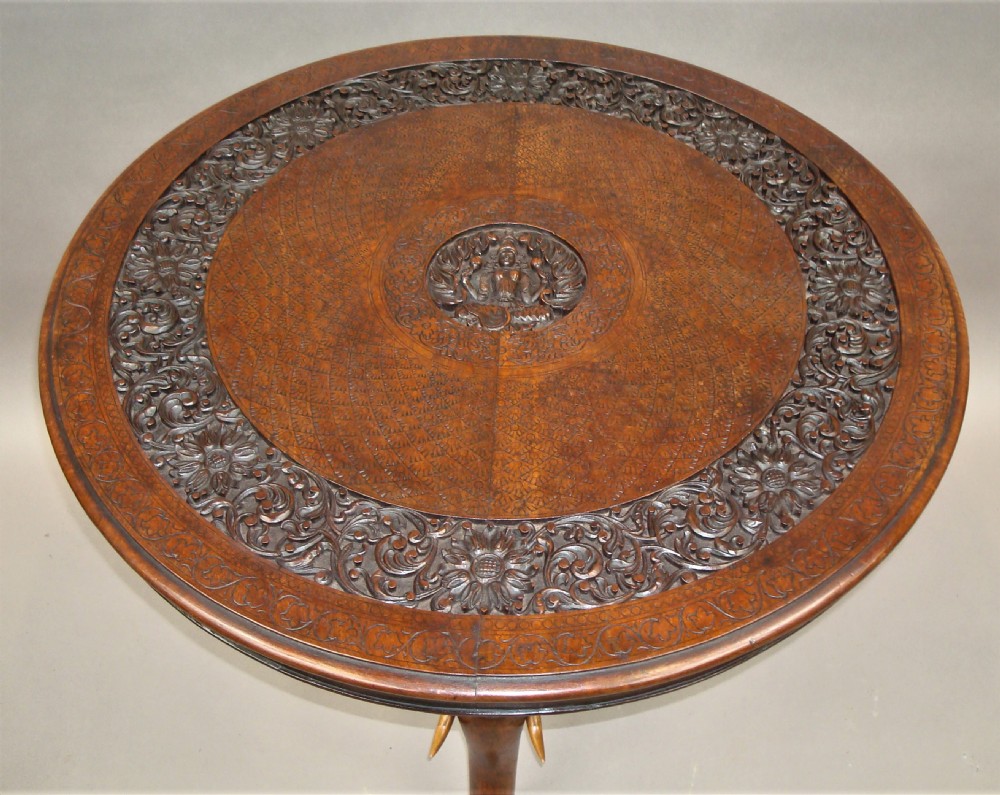 A 19th-century carved teak round table supported by a tripod base shaped like three elephant heads with curving trunks. View XV