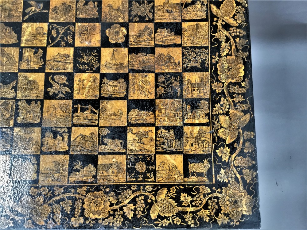 A square black Regency occasional table with an inlaid chessboard top and detailed floral penwork patterns along the frieze and straight legs. View VI