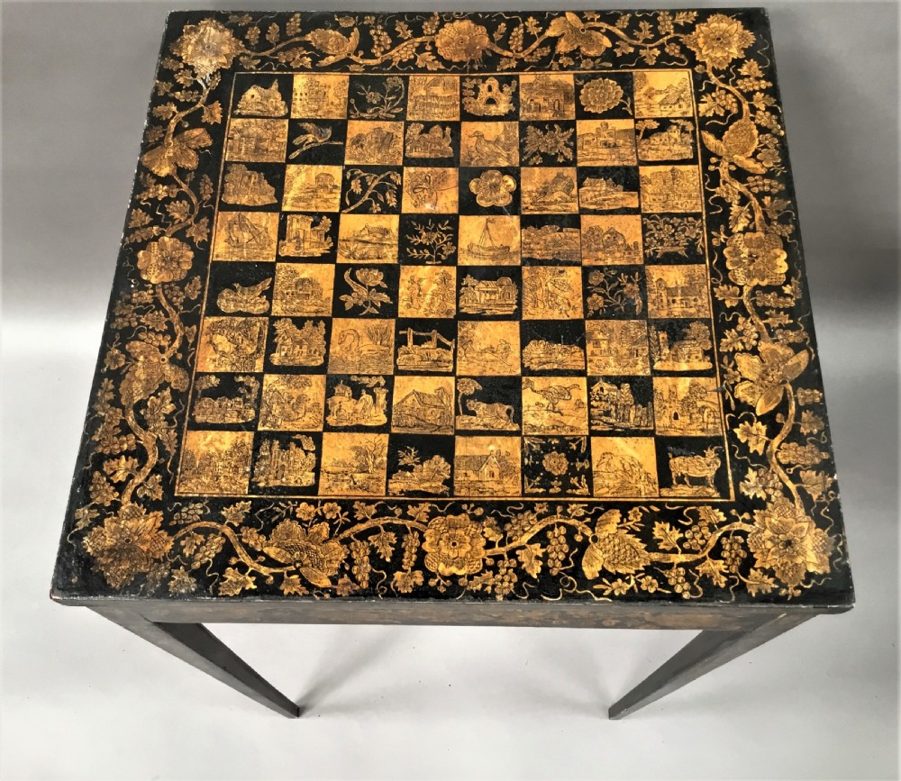 A square black Regency occasional table with an inlaid chessboard top and detailed floral penwork patterns along the frieze and straight legs. View IX