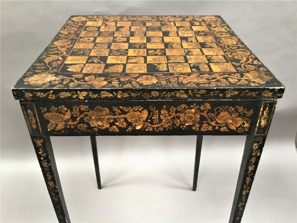 A square black Regency occasional table with an inlaid chessboard top and detailed floral penwork patterns along the frieze and straight legs. View XIV
