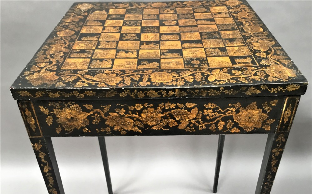 A square black Regency occasional table with an inlaid chessboard top and detailed floral penwork patterns along the frieze and straight legs. View XV