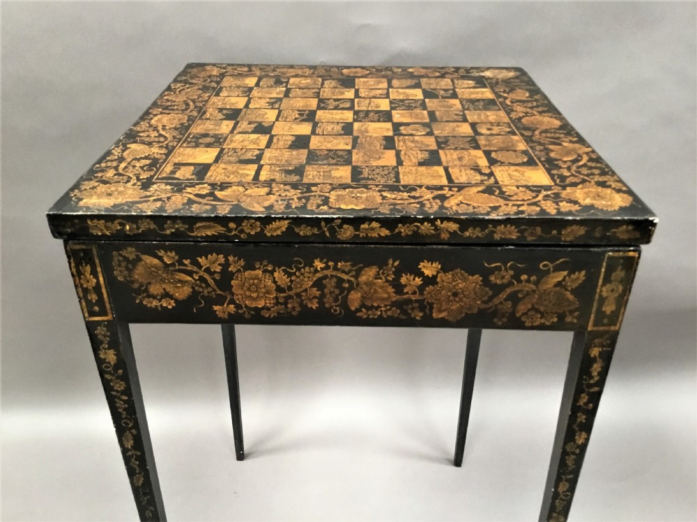 A square black Regency occasional table with an inlaid chessboard top and detailed floral penwork patterns along the frieze and straight legs. View XVII