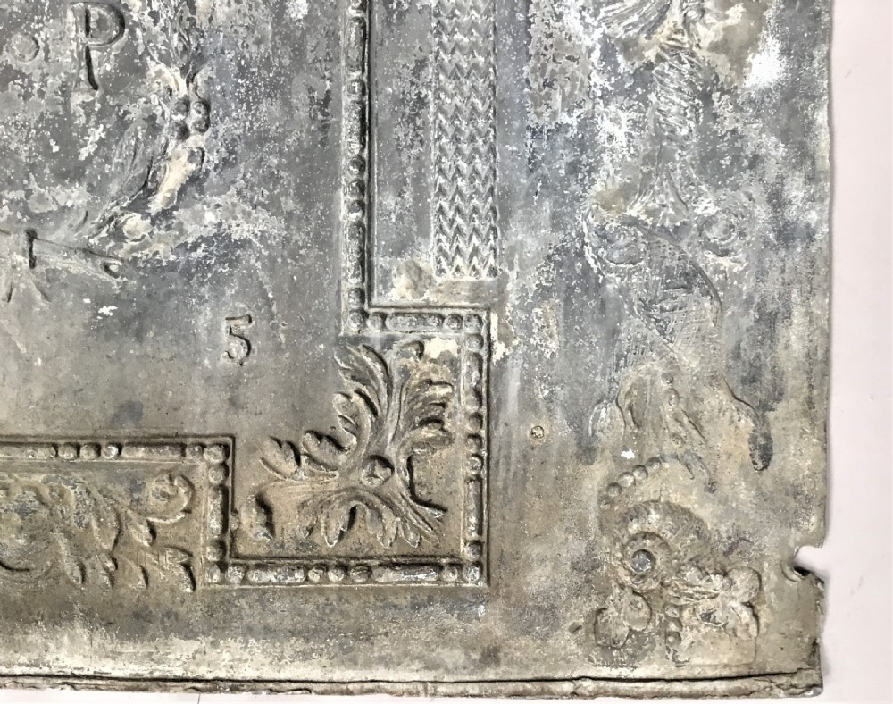 A square cast lead panel dated 1765 featuring a central wreath with monogram PP, acanthus scroll borders, cherub detail, and side relief motifs of dolphins. View X