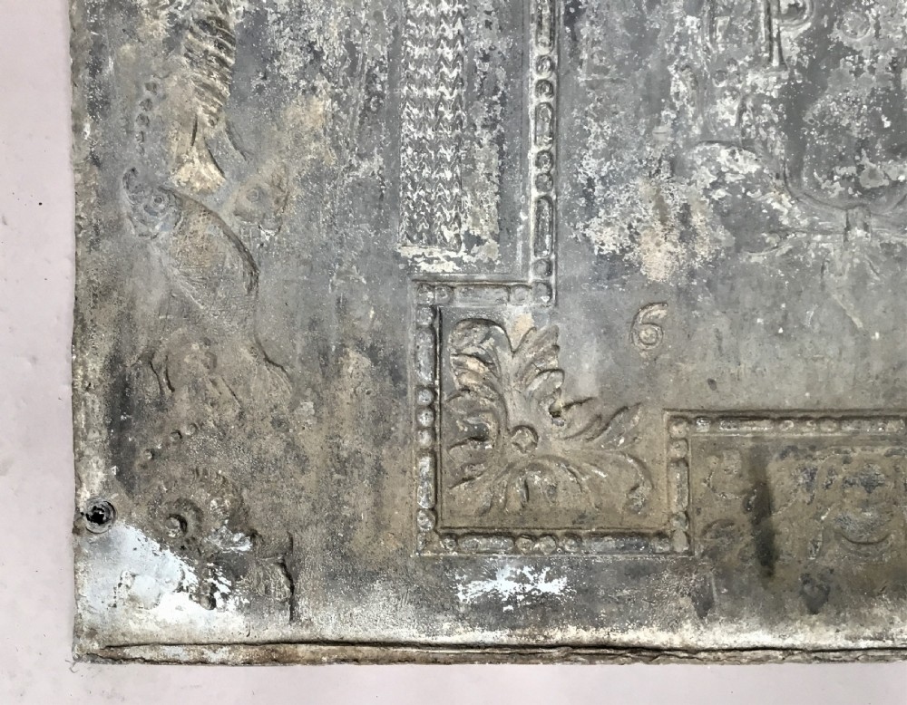 A square cast lead panel dated 1765 featuring a central wreath with monogram PP, acanthus scroll borders, cherub detail, and side relief motifs of dolphins. View XI