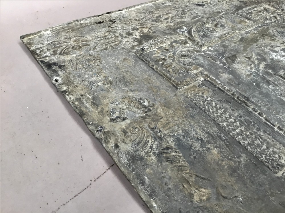 A square cast lead panel dated 1765 featuring a central wreath with monogram PP, acanthus scroll borders, cherub detail, and side relief motifs of dolphins. View XV