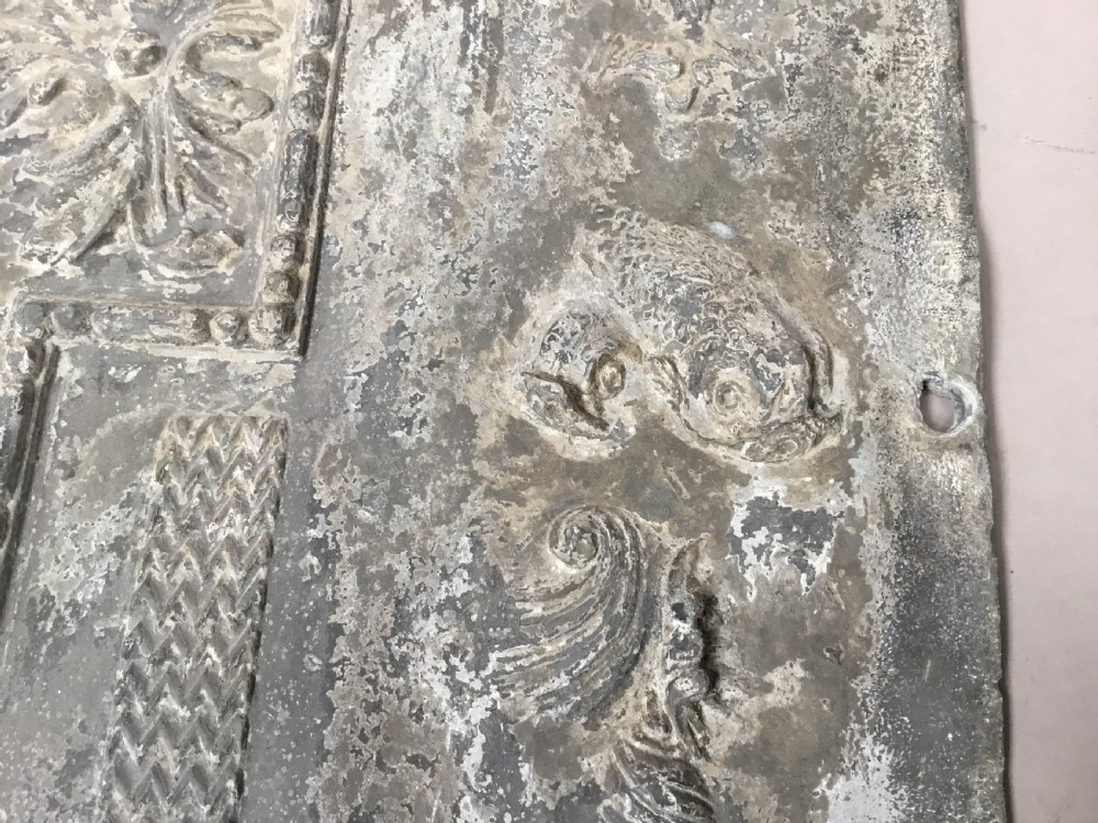 A square cast lead panel dated 1765 featuring a central wreath with monogram PP, acanthus scroll borders, cherub detail, and side relief motifs of dolphins. View XVIII