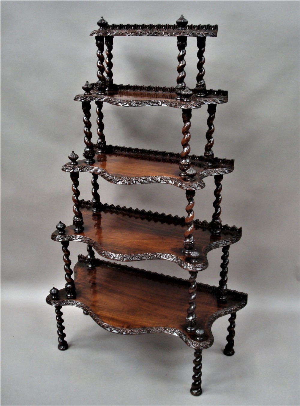 A mid-nineteenth-century dark brown padouk wood whatnot featuring five open tiered shelves supported by barley-twist columns and carved decorative rims.