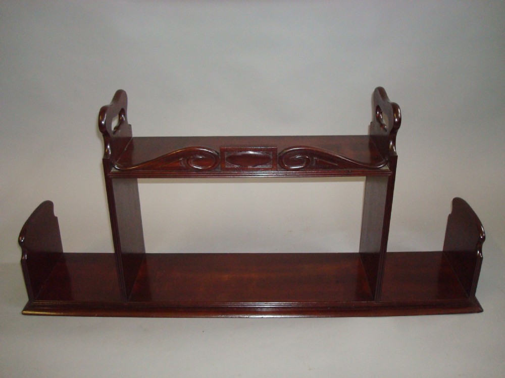 A polished Regency mahogany tabletop book carrier featuring a raised central section with carved cresting, side cut-out handles, and low lateral wings. View VI
