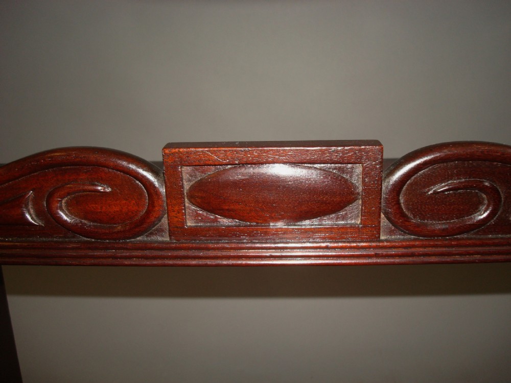A polished Regency mahogany tabletop book carrier featuring a raised central section with carved cresting, side cut-out handles, and low lateral wings. View VII