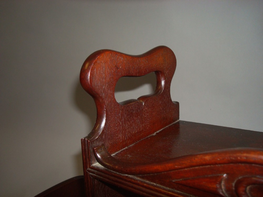 A polished Regency mahogany tabletop book carrier featuring a raised central section with carved cresting, side cut-out handles, and low lateral wings. View VIII