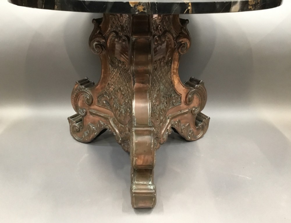 A round black marble low centre table featuring light veining, supported by an ornate copper pedestal base with scrolled feet and carved motifs. View IV