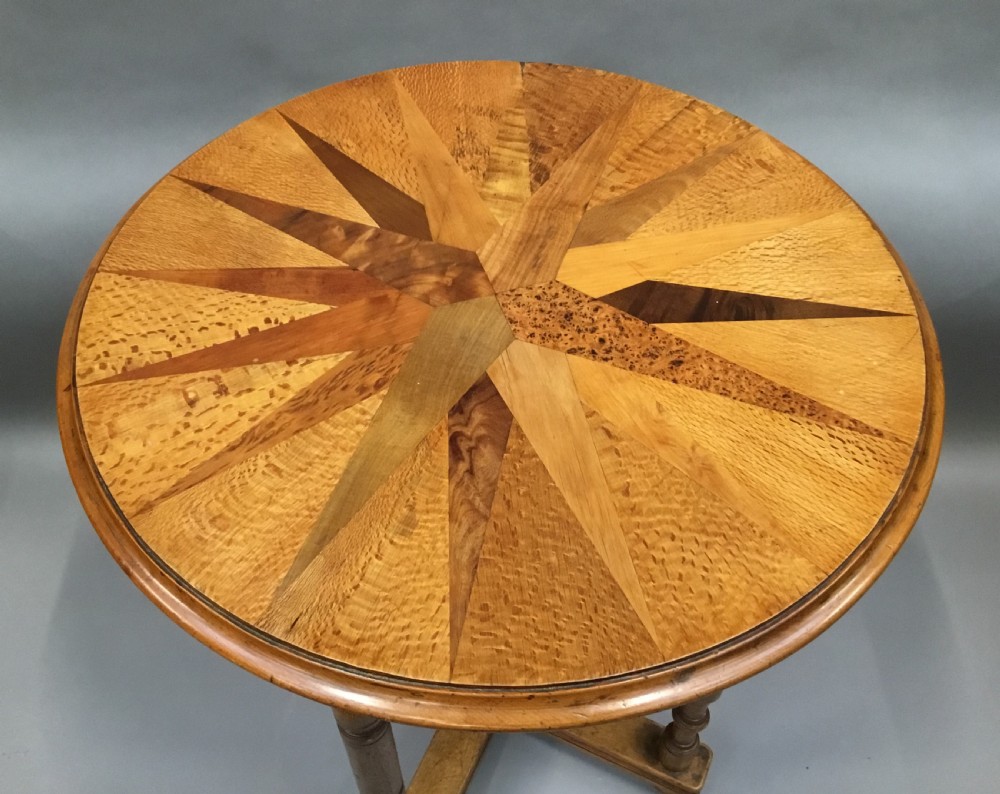 A nineteenth-century circular specimen wood side table featuring a geometric starburst inlaid tabletop supported by four turned legs and an X-frame cross stretcher. View VII