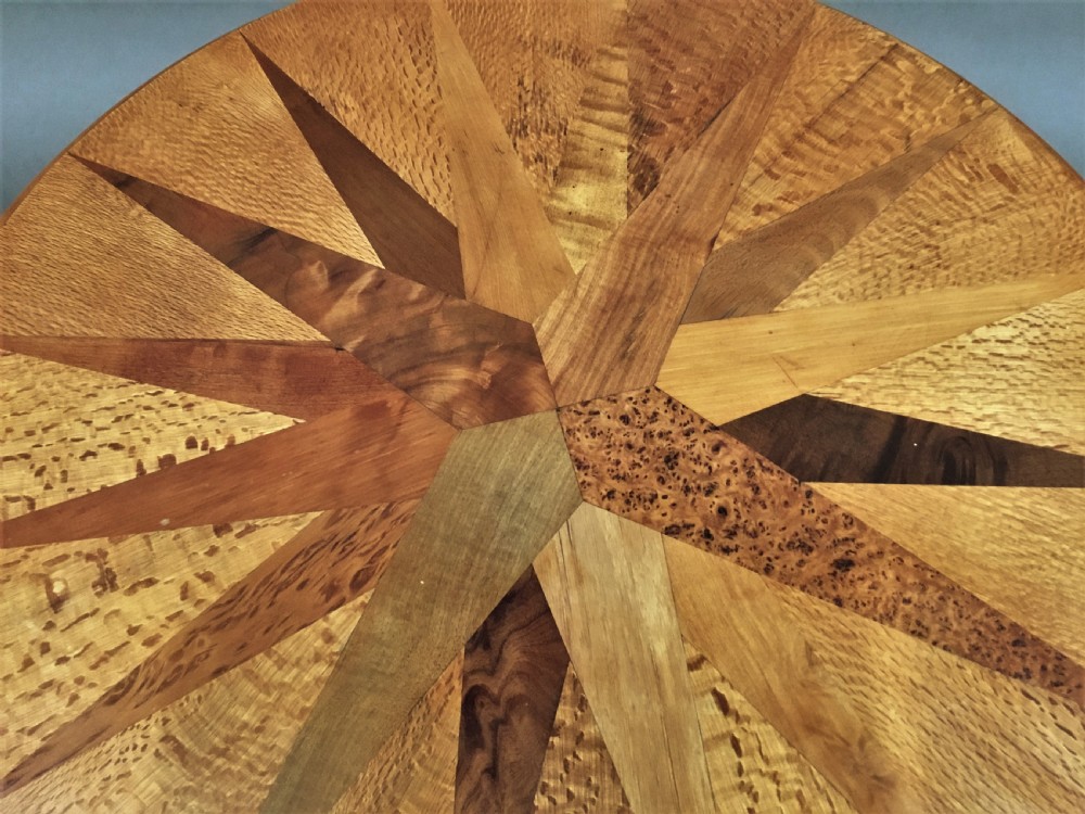 A nineteenth-century circular specimen wood side table featuring a geometric starburst inlaid tabletop supported by four turned legs and an X-frame cross stretcher. View VIII
