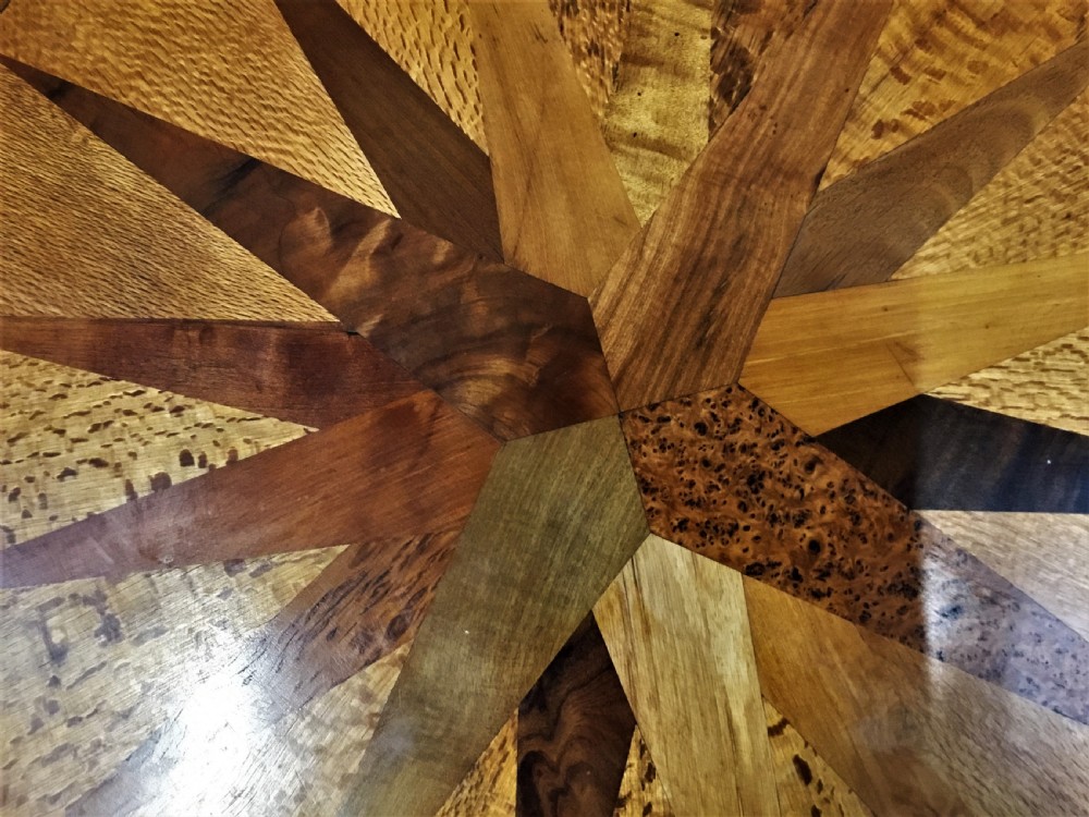 A nineteenth-century circular specimen wood side table featuring a geometric starburst inlaid tabletop supported by four turned legs and an X-frame cross stretcher. View IX