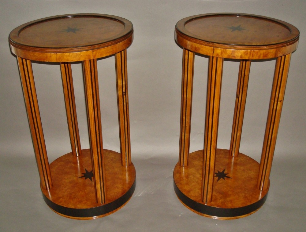 A pair of circular burr elm occasional tables featuring inlaid ebony star motifs, slender vertical legs with black stringing, and an ebony-banded lower tier.