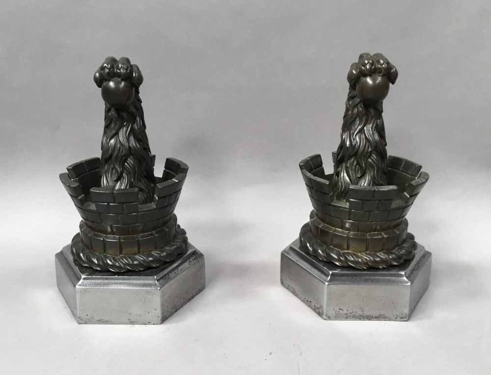 A pair of nineteenth-century bronze door stops featuring a heraldic lion paw holding a ball above a castellated wall, resting on heavy hexagonal bases.