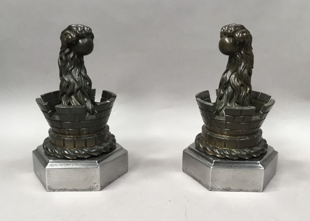 A pair of nineteenth-century bronze door stops featuring a heraldic lion paw holding a ball above a castellated wall, resting on heavy hexagonal bases. View III