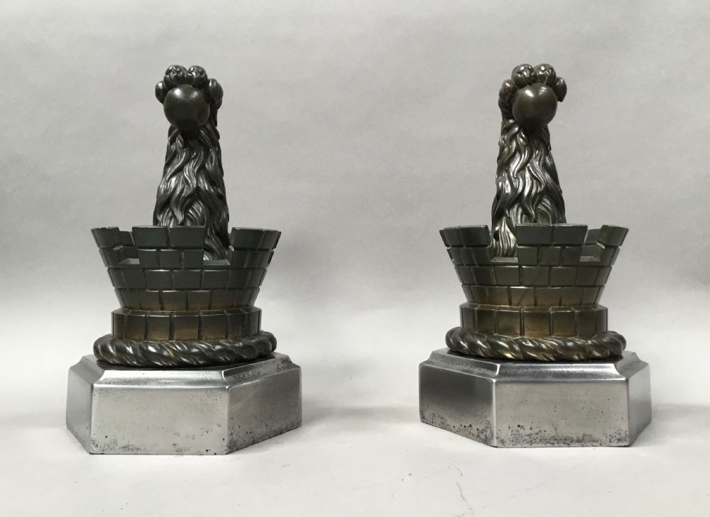 A pair of nineteenth-century bronze door stops featuring a heraldic lion paw holding a ball above a castellated wall, resting on heavy hexagonal bases. View IV