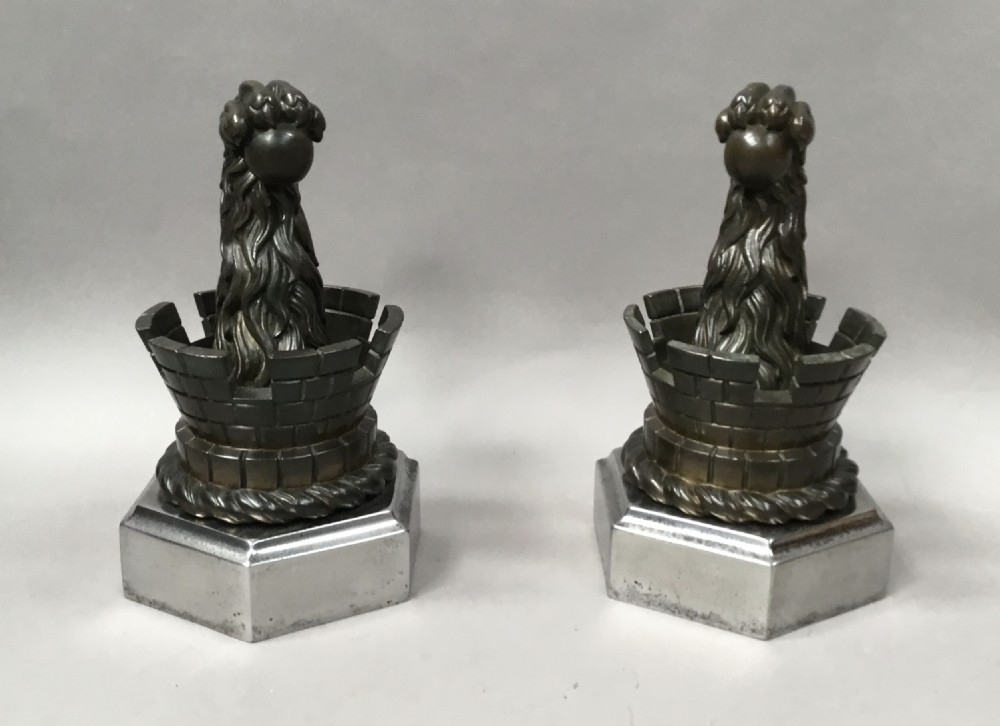 A pair of nineteenth-century bronze door stops featuring a heraldic lion paw holding a ball above a castellated wall, resting on heavy hexagonal bases. View VI