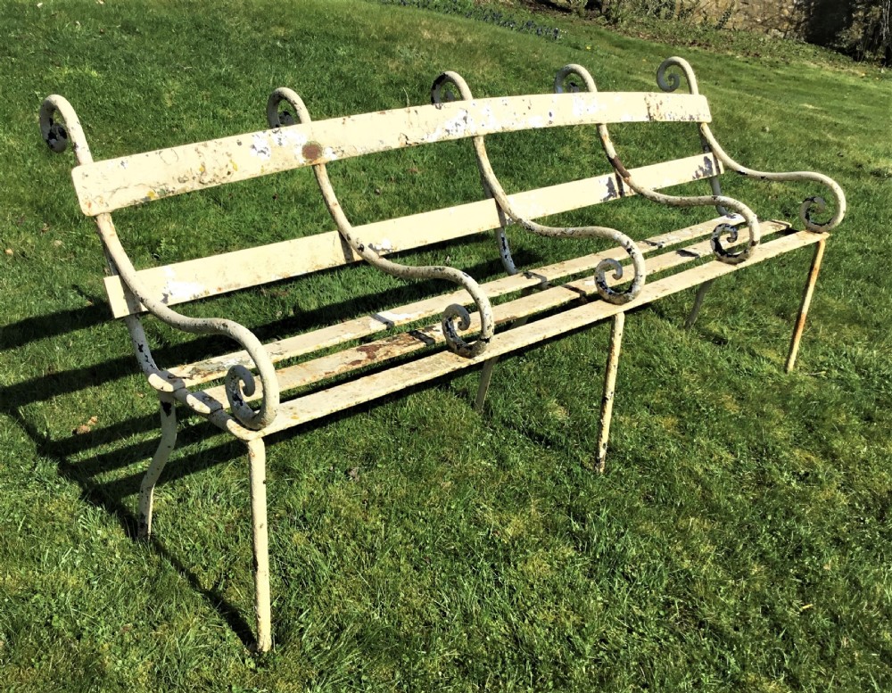 A long nineteenth-century off-white painted iron garden bench featuring scrolled armrests and slatted back supports with weathered patina. View XI