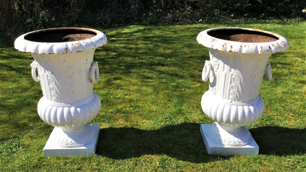 A pair of white painted 19th-century cast iron garden urns featuring fluted rims, side ring handles, gadrooned lower bodies, and square plinth bases. View III