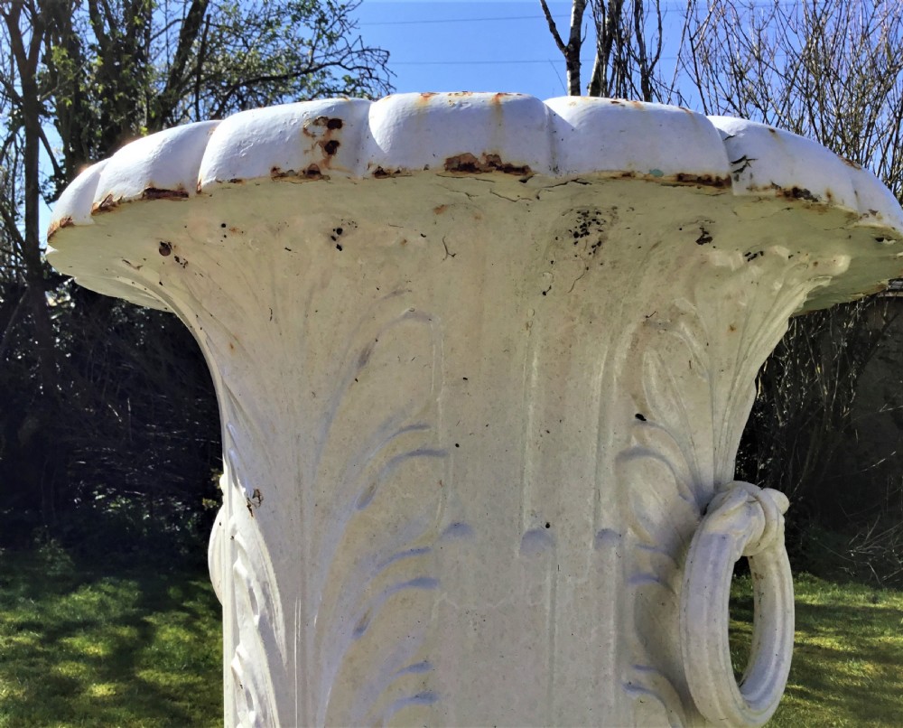 A pair of white painted 19th-century cast iron garden urns featuring fluted rims, side ring handles, gadrooned lower bodies, and square plinth bases. View XII