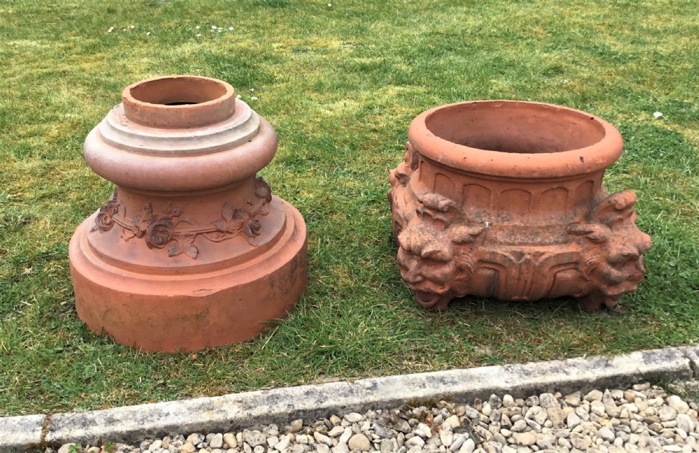 A nineteenth-century terracotta garden urn featuring sculpted mask faces around the body and floral swags on a pedestal base. View XI