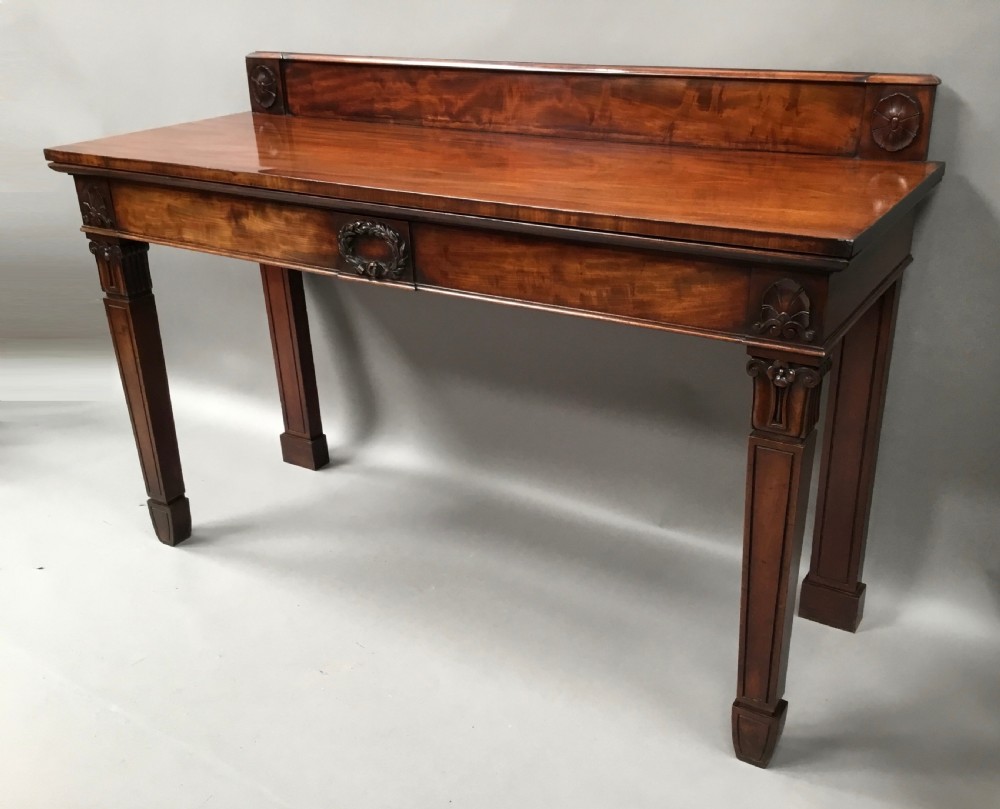 A Regency mahogany side serving table featuring a low upstand with carved rosettes, fluted square tapered legs with ionic capitals, and a flame mahogany apron. View III