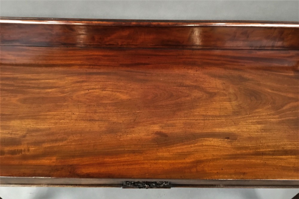 A Regency mahogany side serving table featuring a low upstand with carved rosettes, fluted square tapered legs with ionic capitals, and a flame mahogany apron. View V