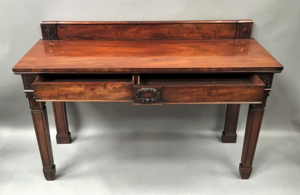 A Regency mahogany side serving table featuring a low upstand with carved rosettes, fluted square tapered legs with ionic capitals, and a flame mahogany apron. View VIII