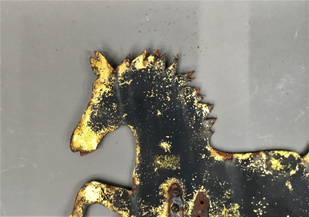 A nineteenth-century black iron horse silhouette weathervane with trace gold leaf detailing, mounted on a central spindle above a directional arrow. View III