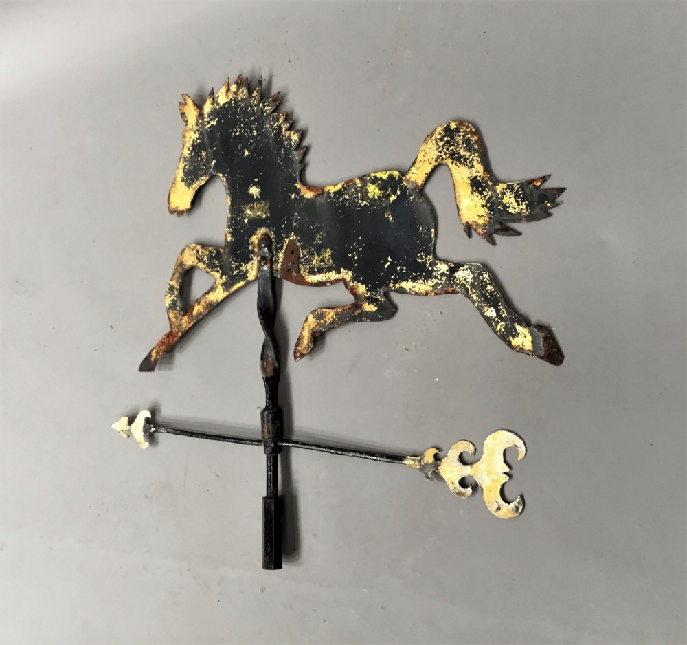 A nineteenth-century black iron horse silhouette weathervane with trace gold leaf detailing, mounted on a central spindle above a directional arrow. View VII