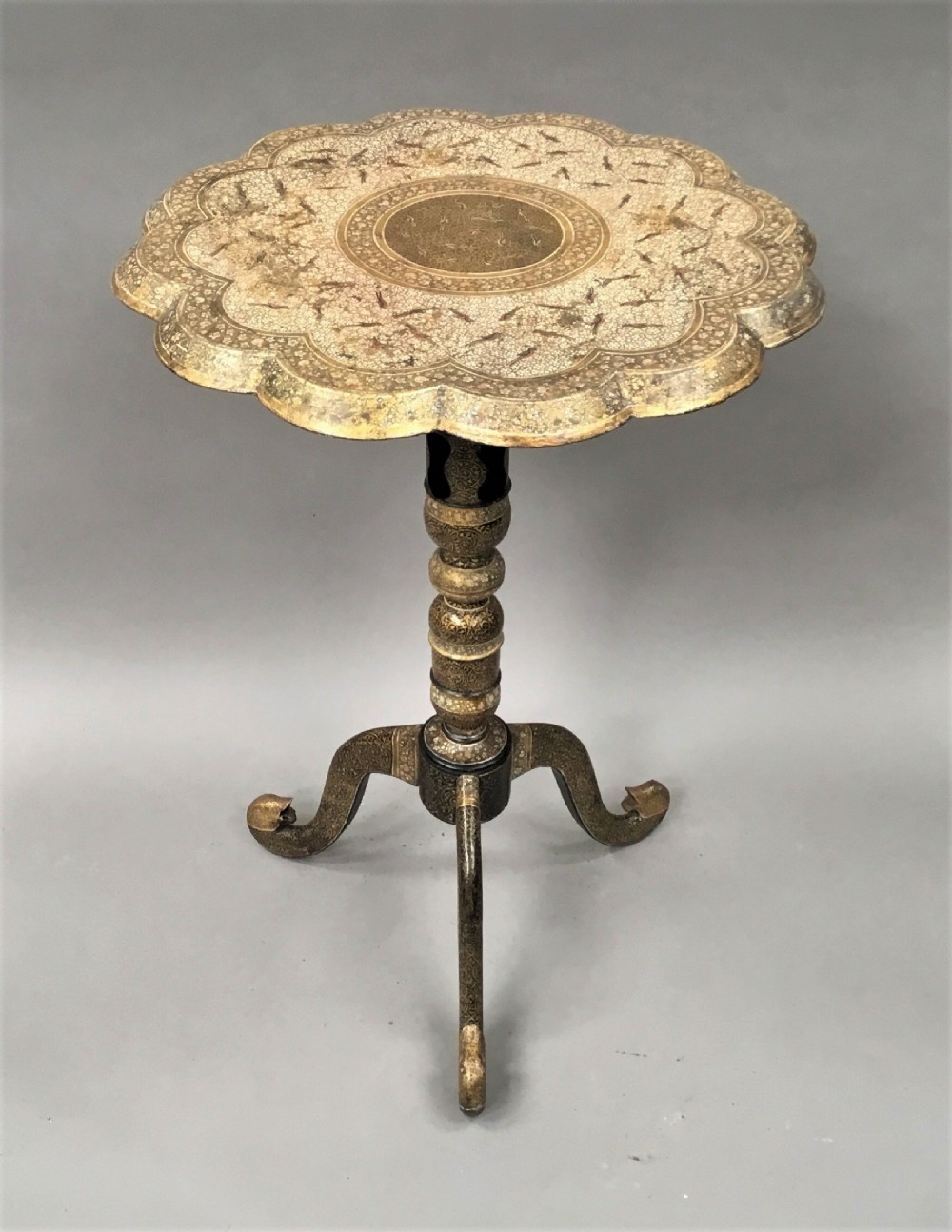 A late 19th-century Kashmiri occasional table with a scalloped top, central turned pedestal, tripod base, and gold floral paintwork.