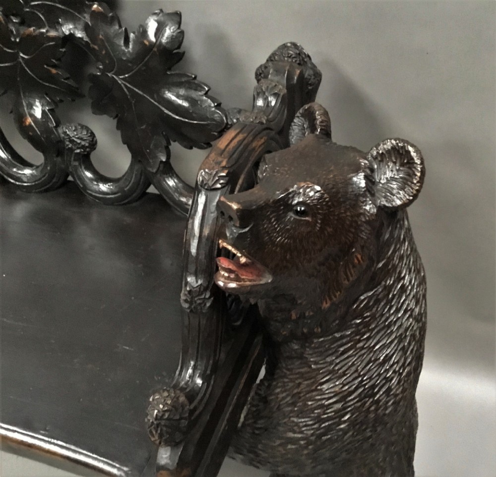 A 19th-century dark carved wood hall seat supported by two sculptural standing bear figures with a carved leaf motif backrest. View XIII