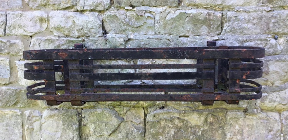 A pair of early 20th-century black wrought iron window boxes with slatted horizontal straps, rounded ends, and top mounting hooks resting on gravel. View IV