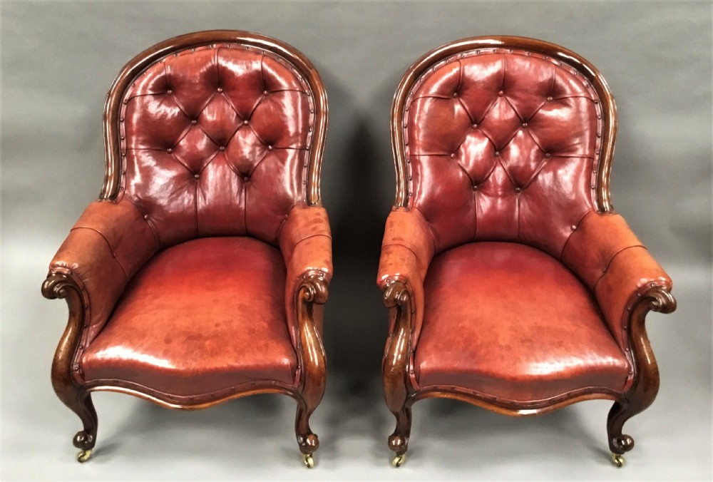 A pair of Victorian mahogany armchairs upholstered in button-backed deep red leather featuring scrolled arms and front cabriole legs on brass castors. View III